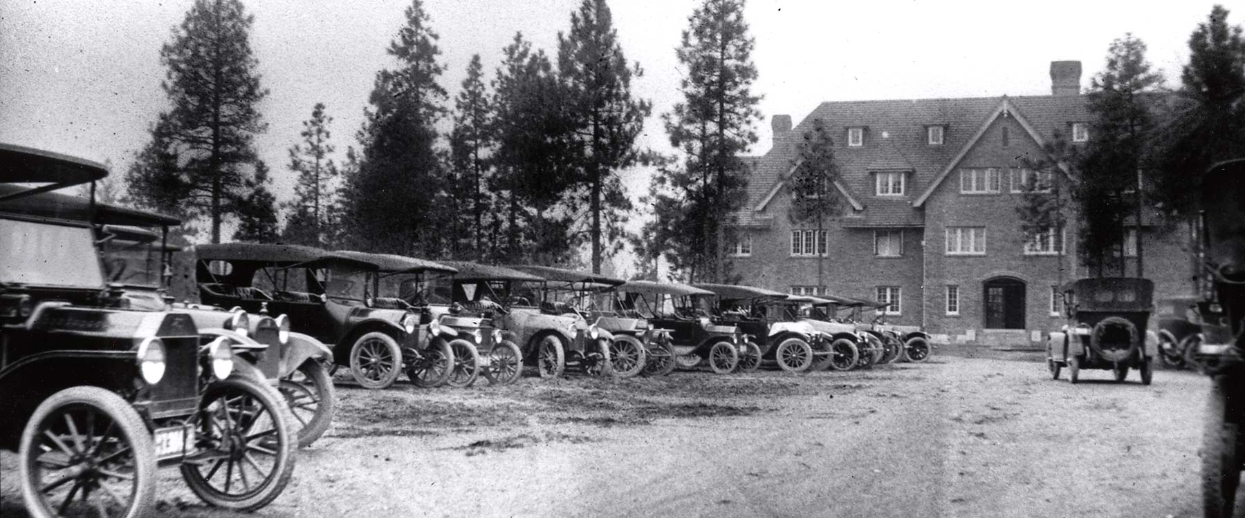 Vintage black-and-white photo of an original Whitworth academic building with 1920-30s-style cars parked outside.