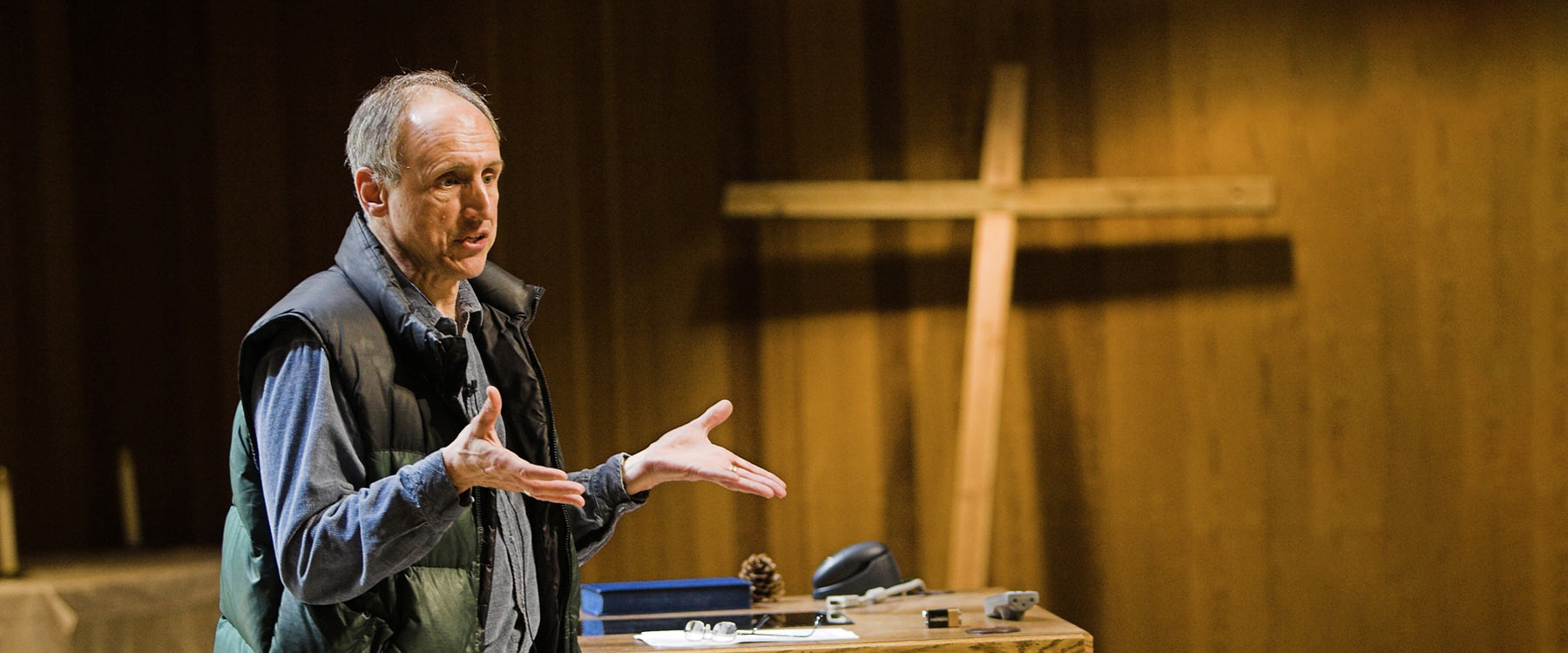 A professor gestures with outstretched hands during a theology lecture in the chapel.