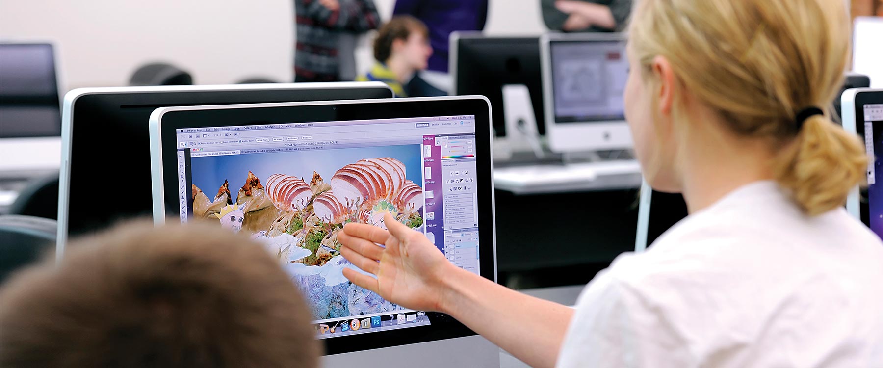 A student points to a computer screen. On the screen is an eclectic and colorful design.