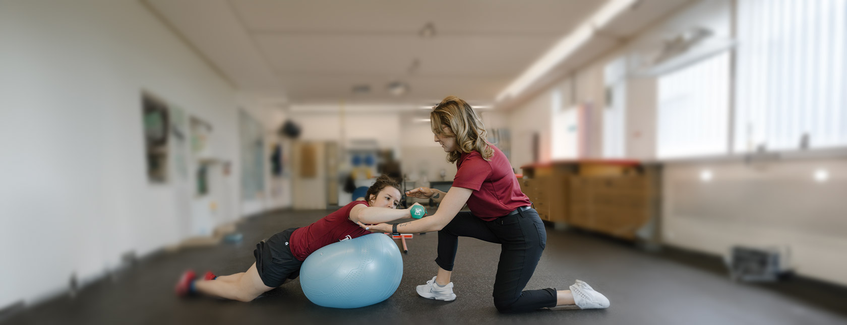 Two students work together to practice rehabilitation techniques using balls and weights.