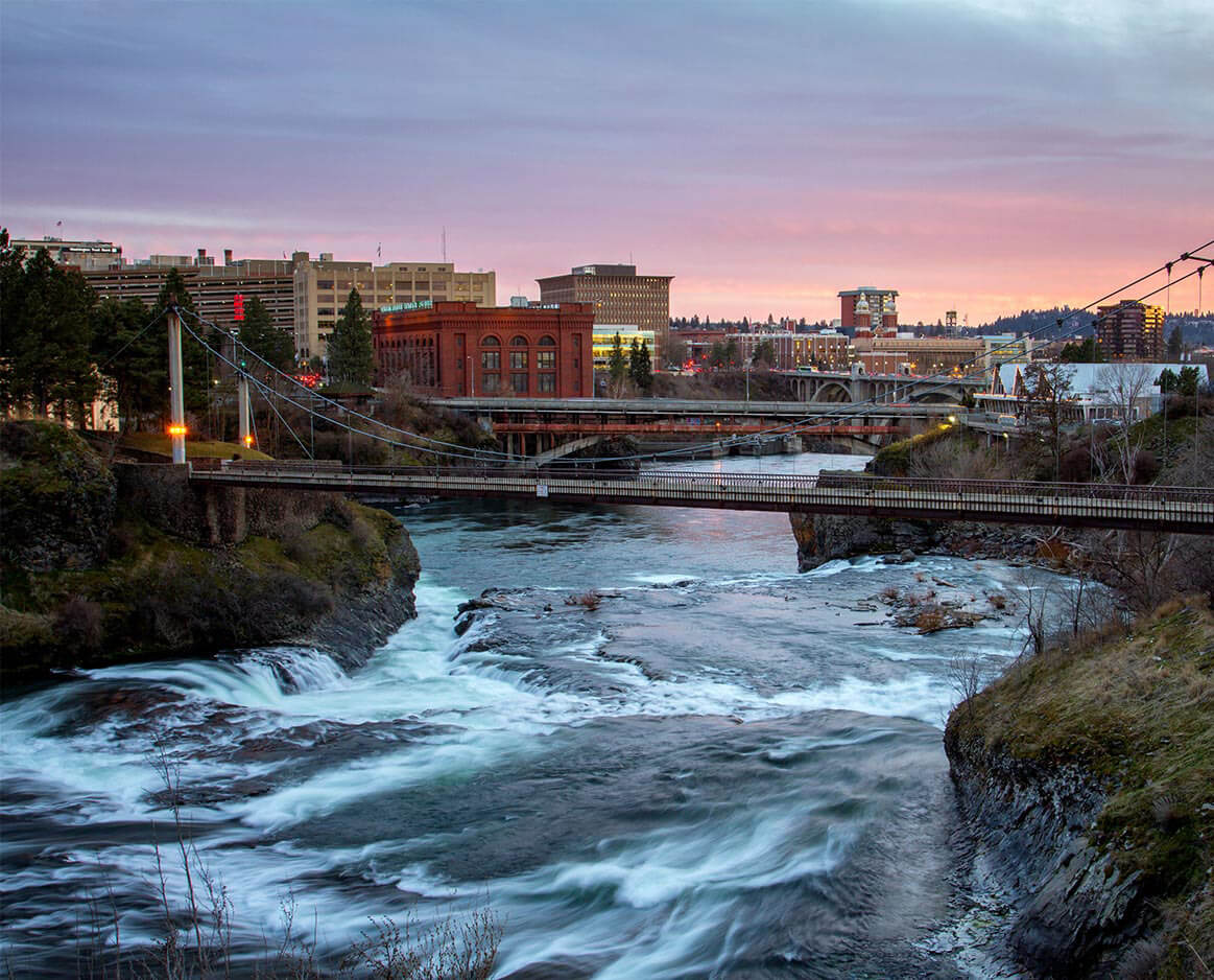 Bridges over the Spokane river at dusk with the city in the background.