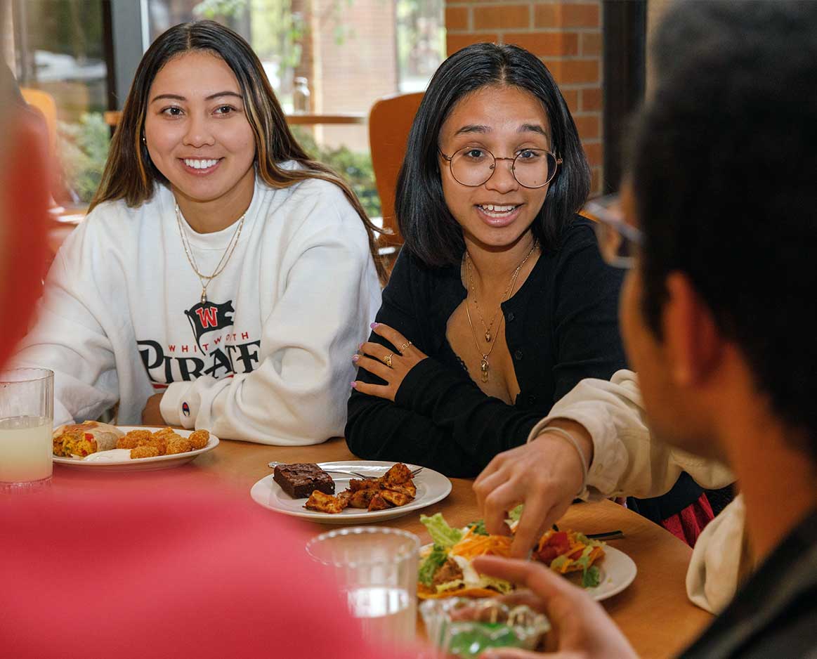 Multiple students converse over a meal in the Whitworth dining hall