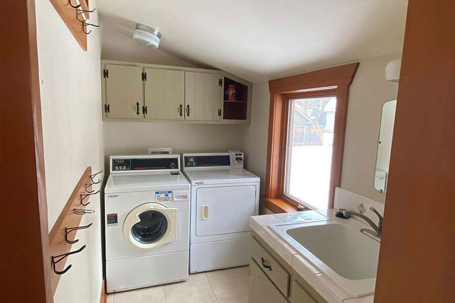 Laundry room with washer, dryer, sink, built-in cabinets and a window with natural light.