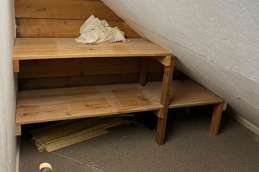 A small attic space with a slanted roof and wooden shelves.