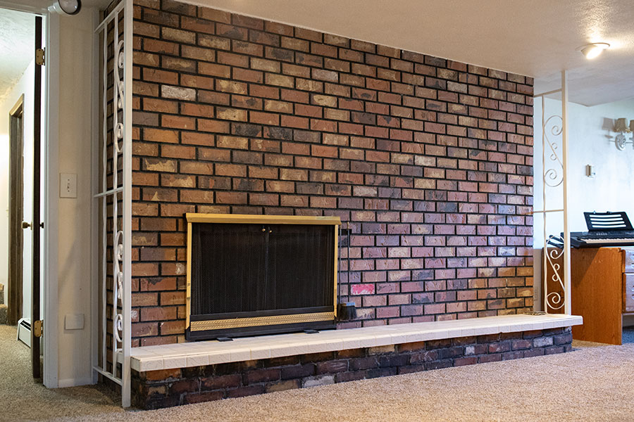 Cozy open space featuring a large brick fireplace with decorative metal details on the side.