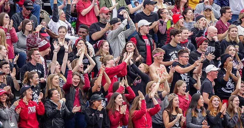 A large, enthusiastic crowd of sports fans cheer in the stadium stands at Whitworth.