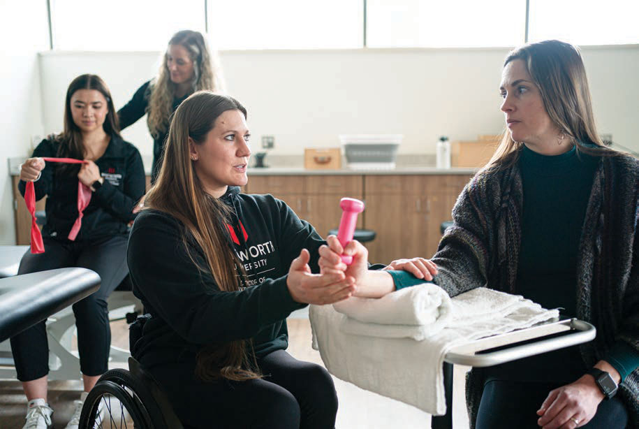 McClammer demonstrates teaching an arm strengthening exercise to a Whitworth professor using a small dumbbell.