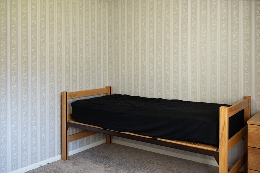 Classic wallpapered bedroom with gray carpet and a twin bed.