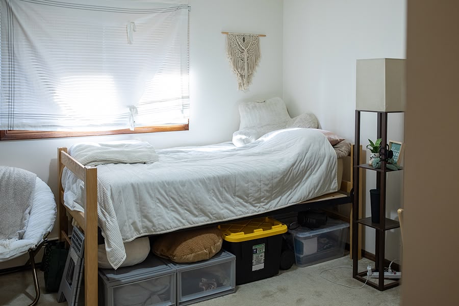 Cozy bedroom with a large window and a single bed with organized storage boxes underneath.