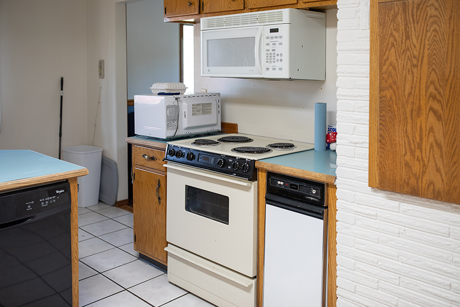 Corner of a spacious kitchen with dishwater, two microwaves, and an oven with an electric range.